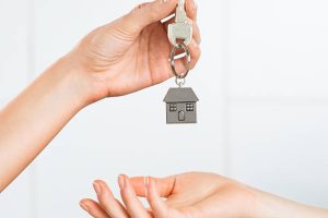 Echange d'un porte clé en forme de maison entre les mains de deux personnes